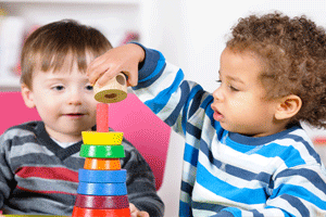 Toddler care program with two kids stacking toys