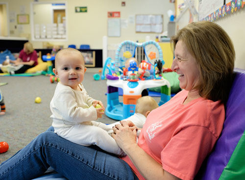 Daycare associate playing with baby and the baby looks happy 