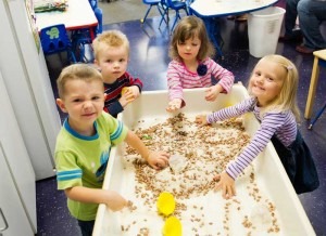 A group of preschool children playing in a sandbox at a daycare in Columbus Ohio